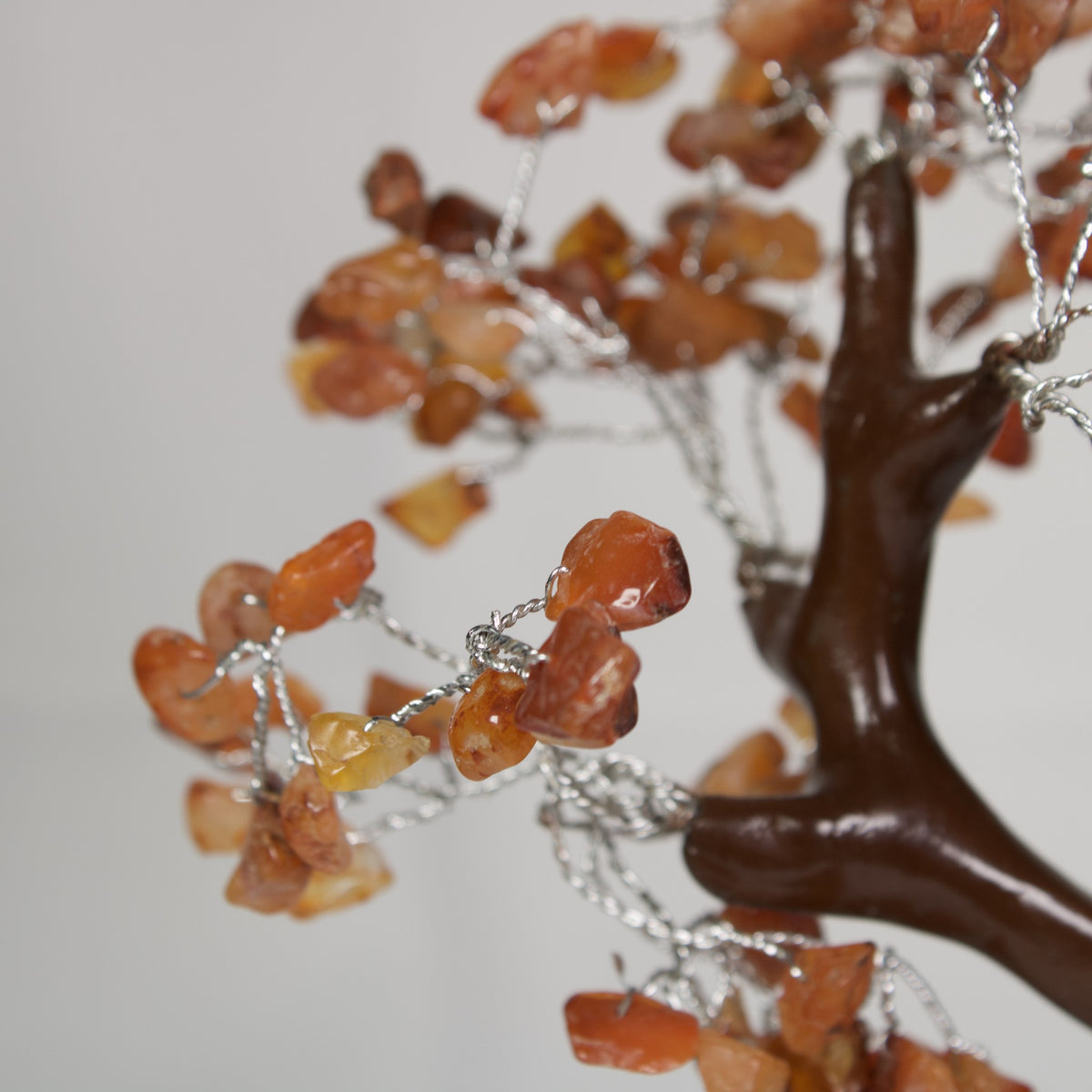 Close-up of orange carnelian chips on silver-tone wire branches