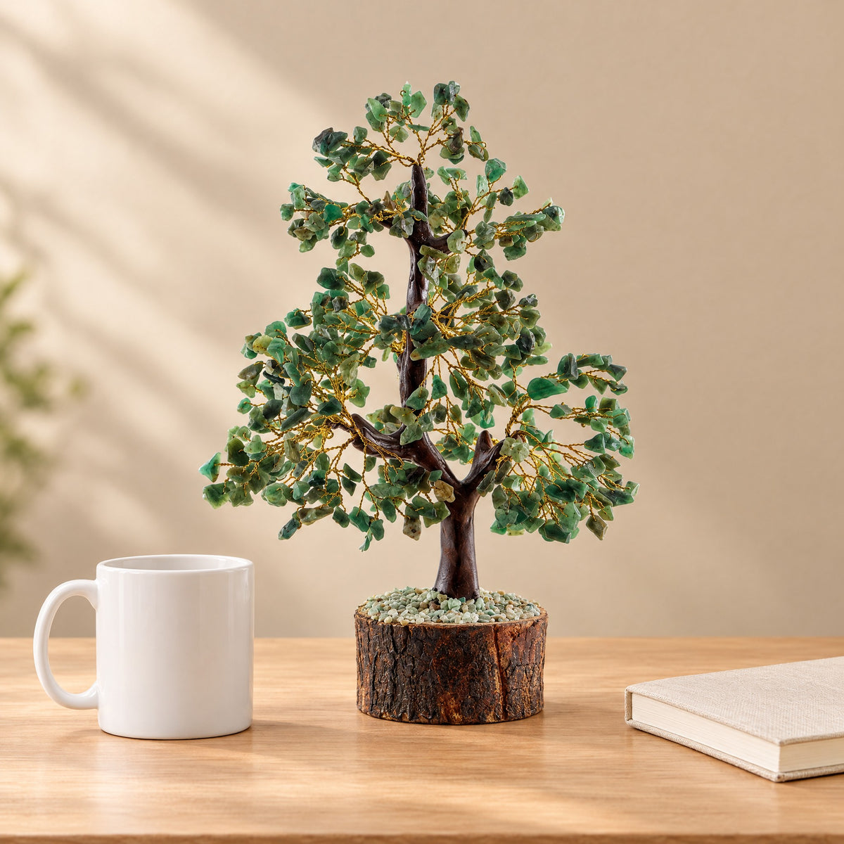 Green aventurine crystal tree on a desk beside a coffee mug for size