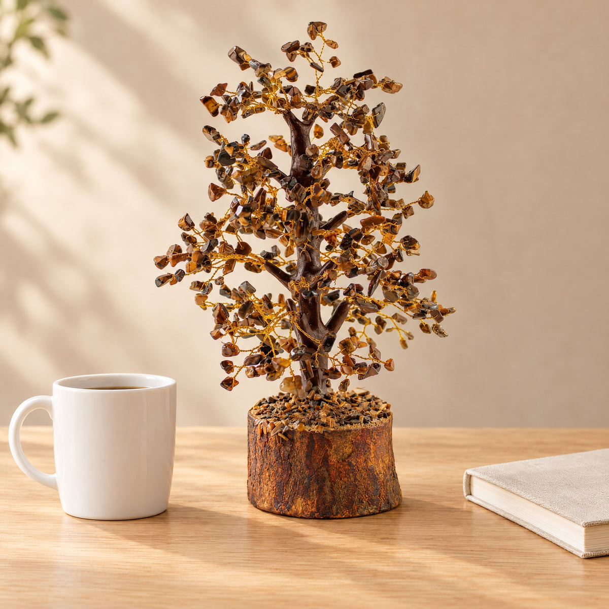 Tiger eye crystal tree on a desk beside a coffee mug for size