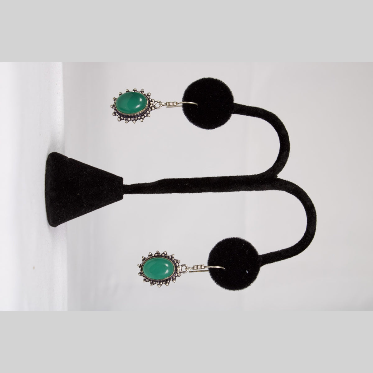 Unedited photo of the green onyx drop earrings on a stand