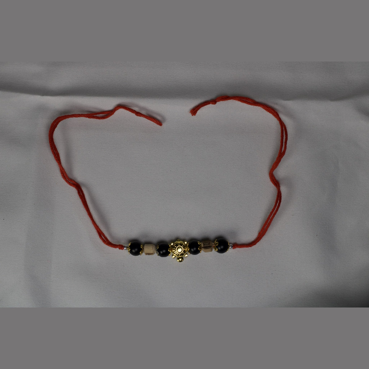 Red string bracelet laid flat with its long tie ends