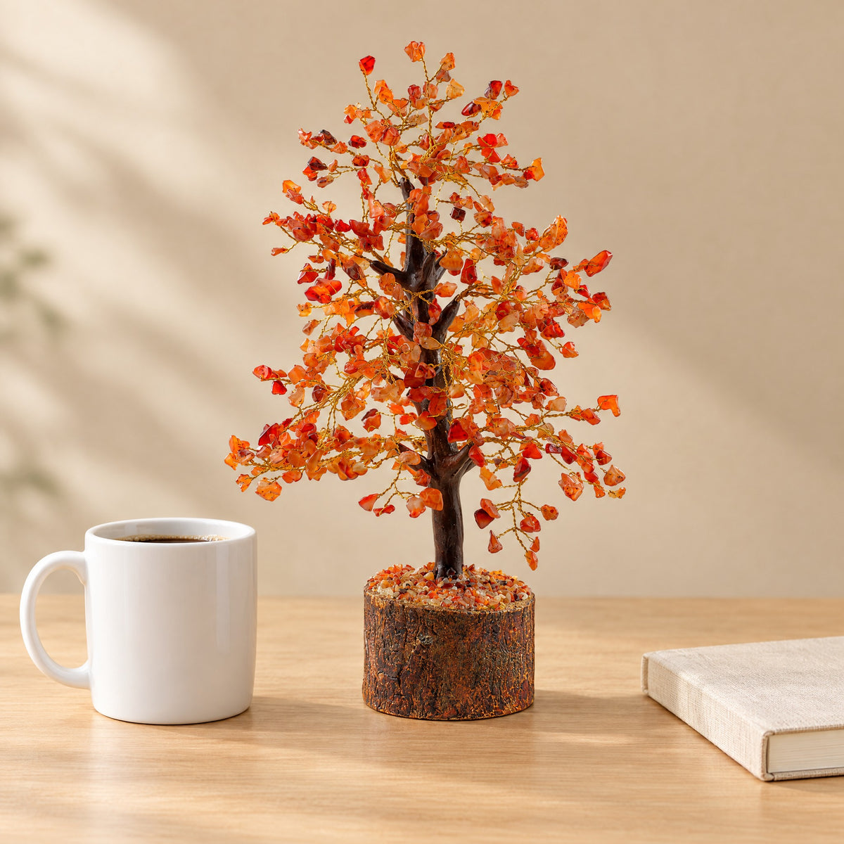 Carnelian gemstone tree on a desk beside a coffee mug for size