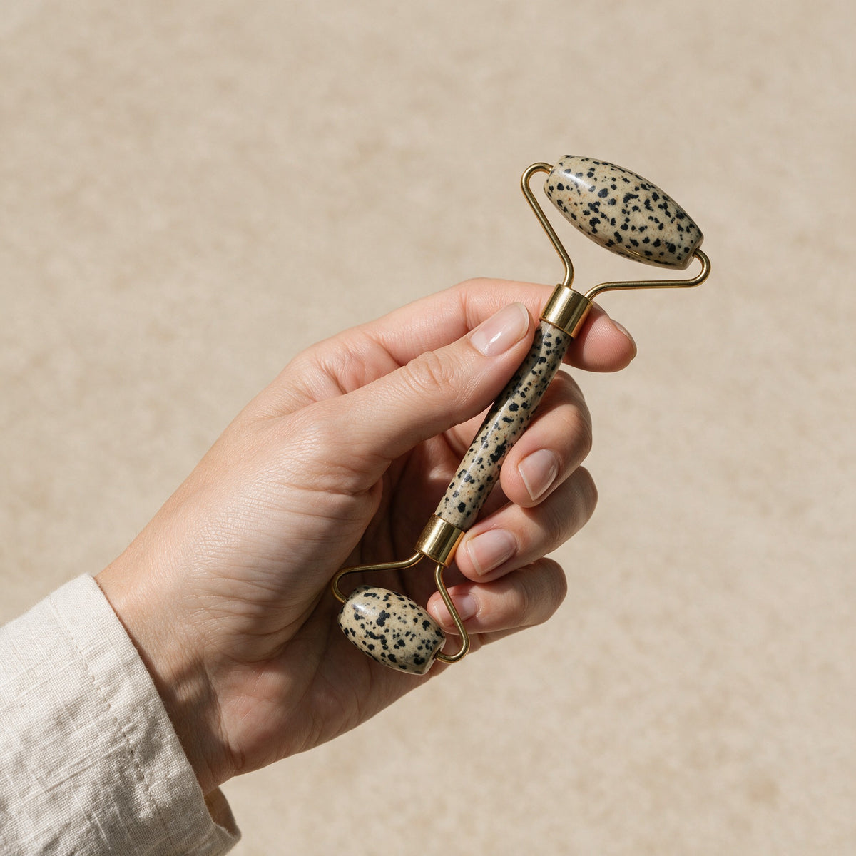 Dalmatian jasper face roller held in a hand for size