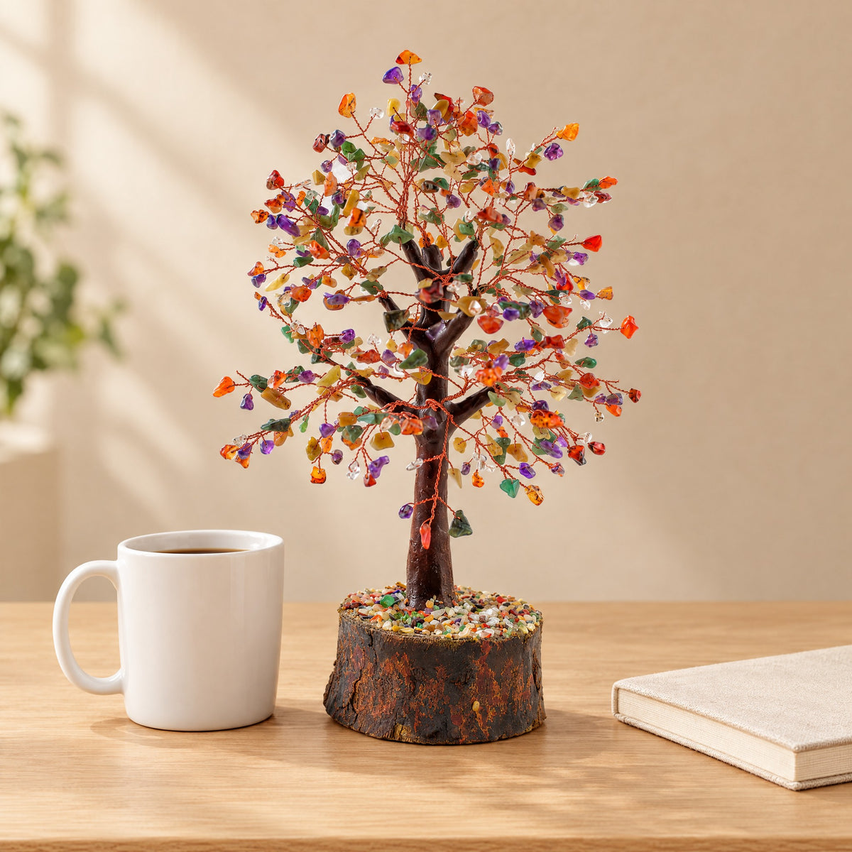 Multi-colour gemstone tree on a desk beside a coffee mug for size