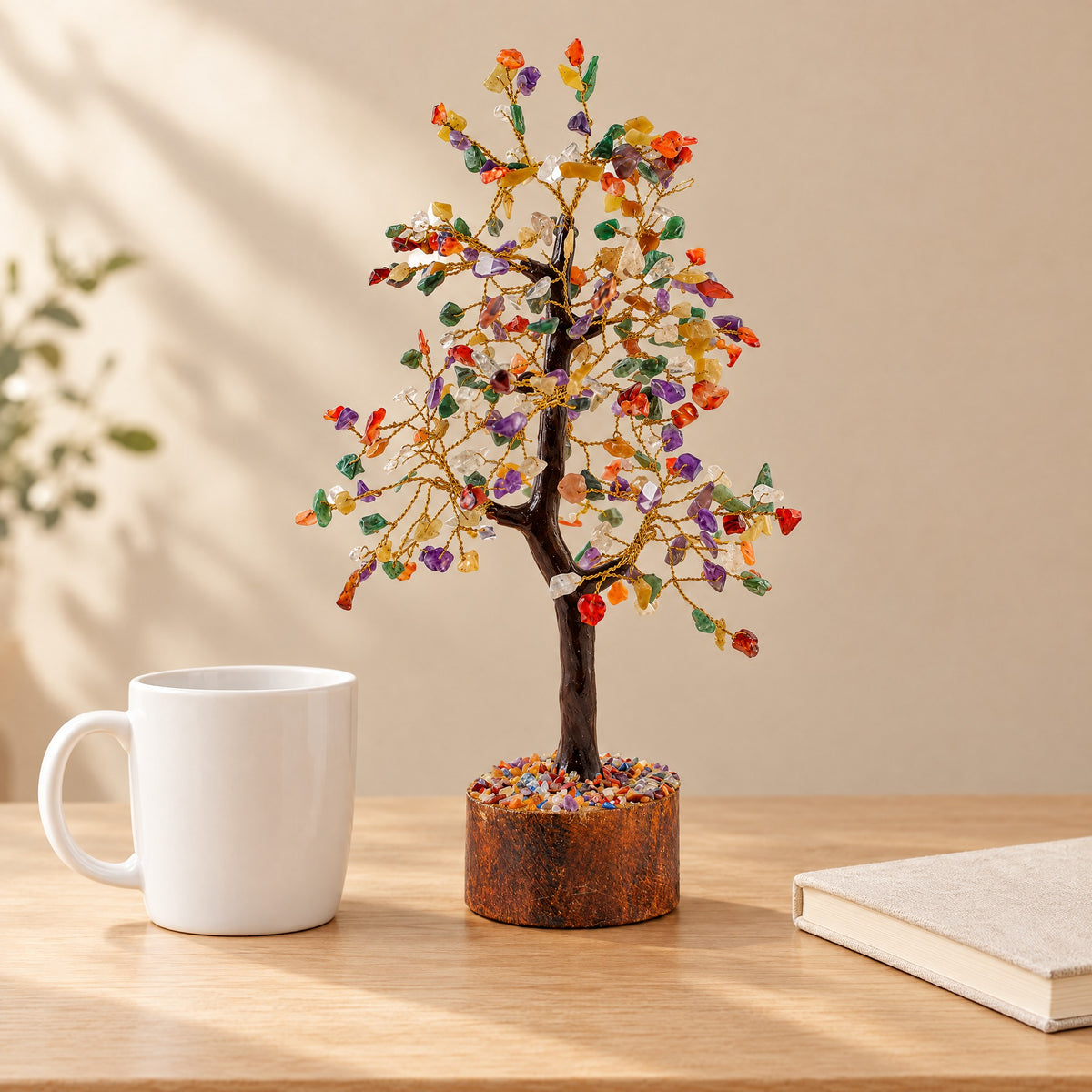 Multi-colour gemstone tree on a desk beside a coffee mug for size
