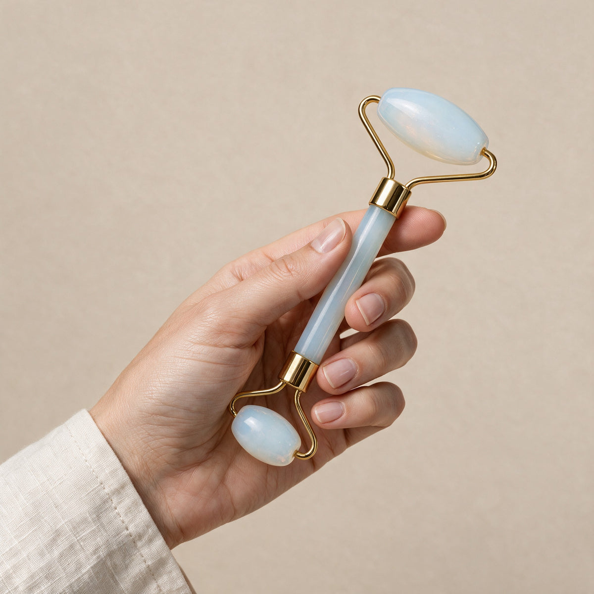 Opal face roller with gold-tone frame held in a hand for size