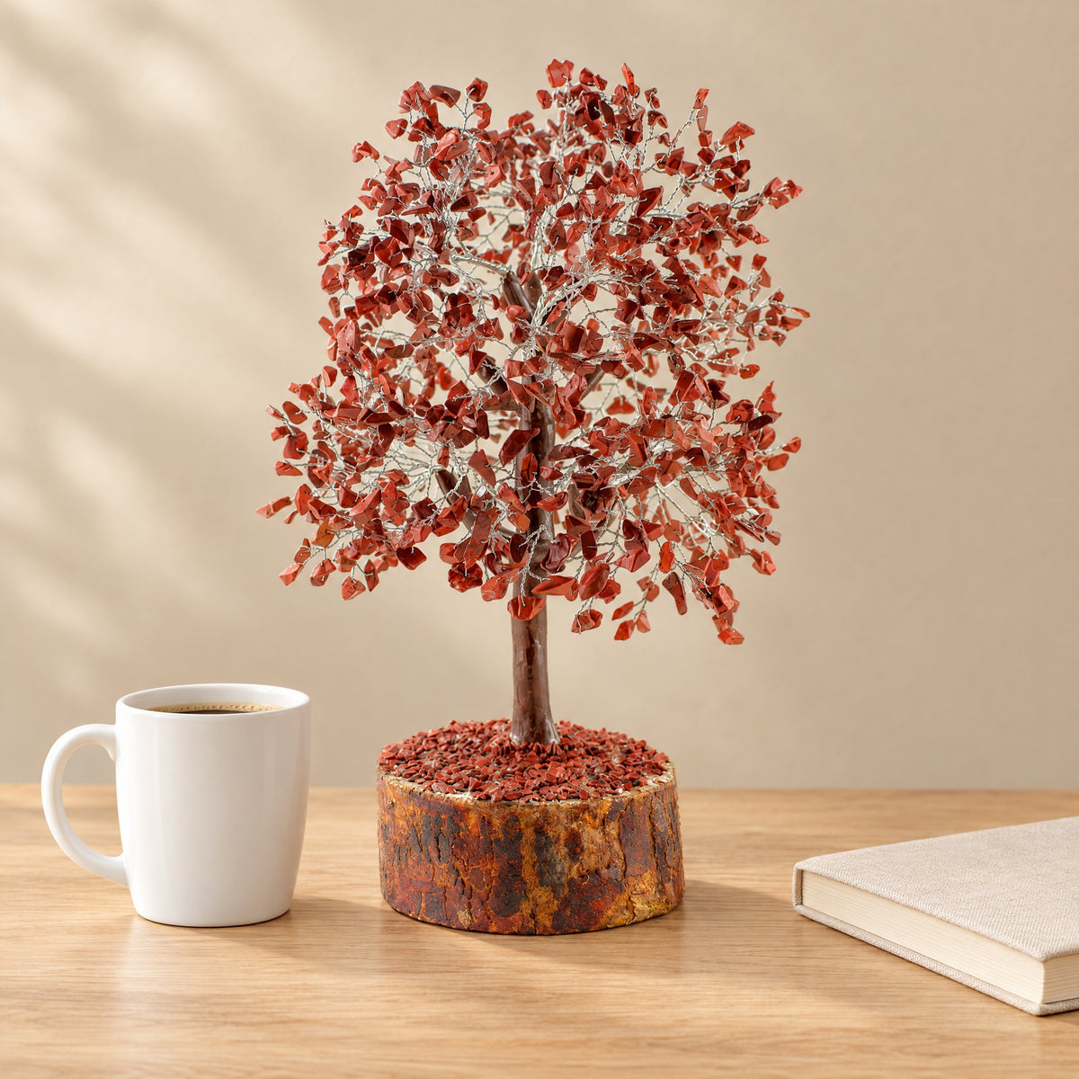 Red jasper gemstone tree on a desk beside a coffee mug for size
