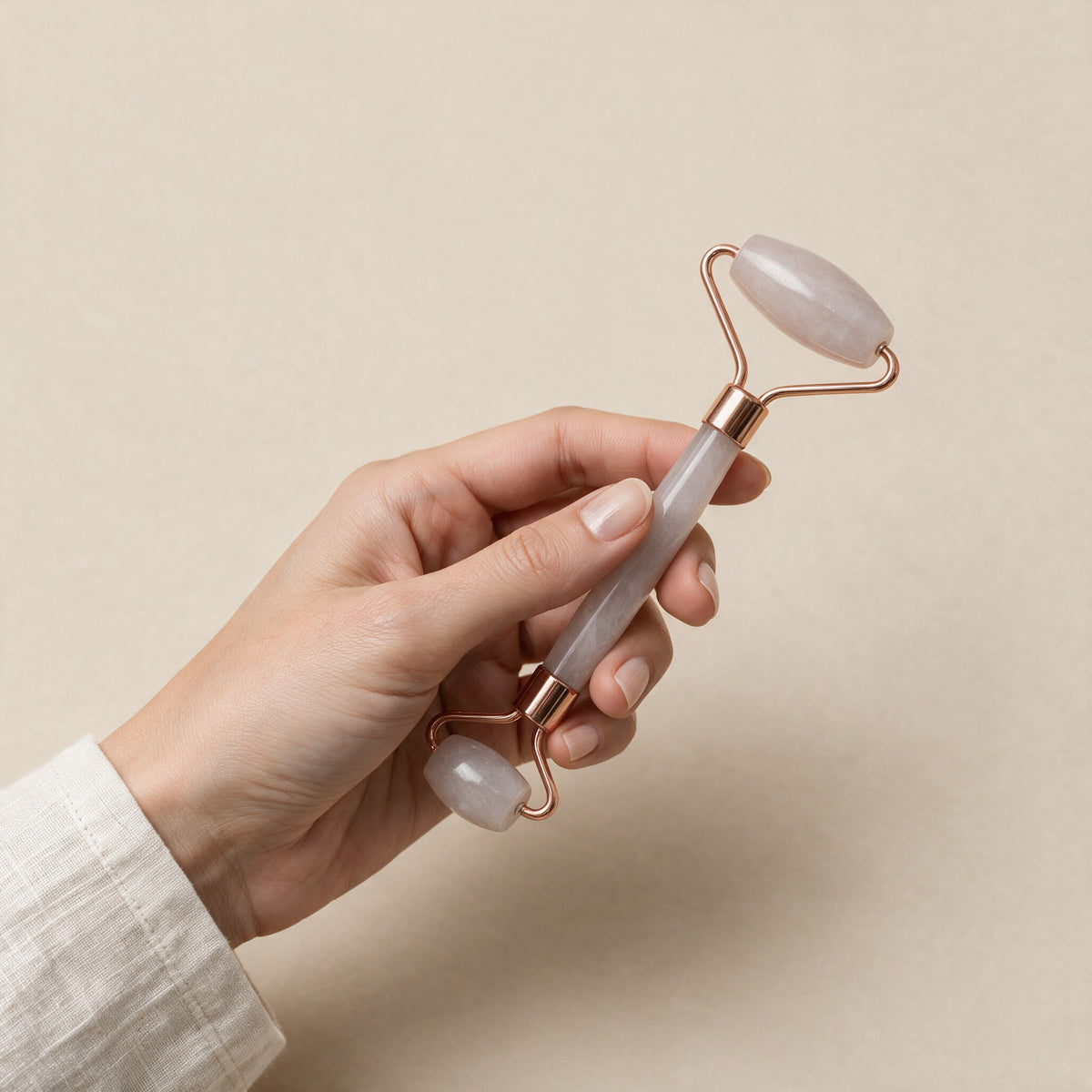 Rose quartz face roller held in a hand for size