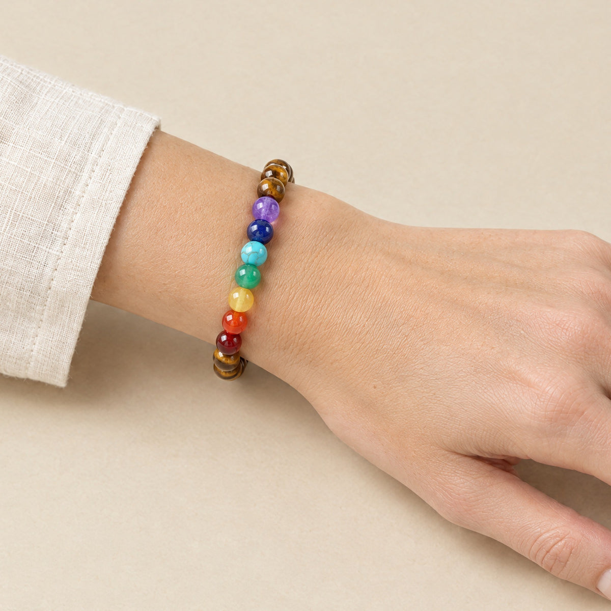 Seven chakra and tiger eye bracelet worn on a woman's wrist