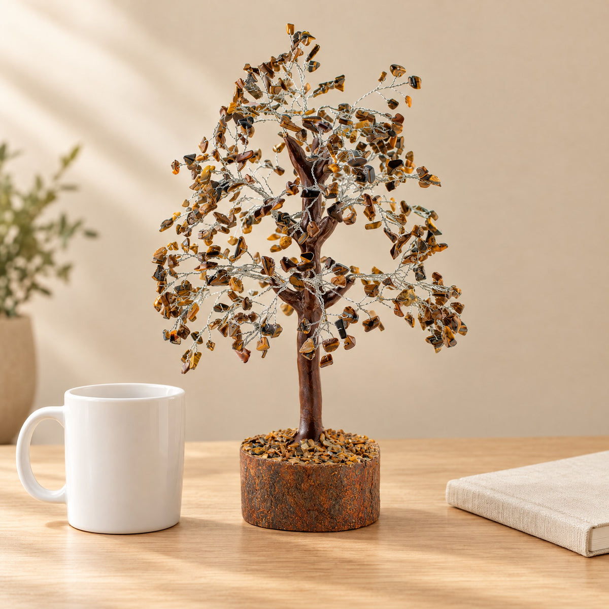 Tiger eye gemstone tree on a desk beside a coffee mug for size
