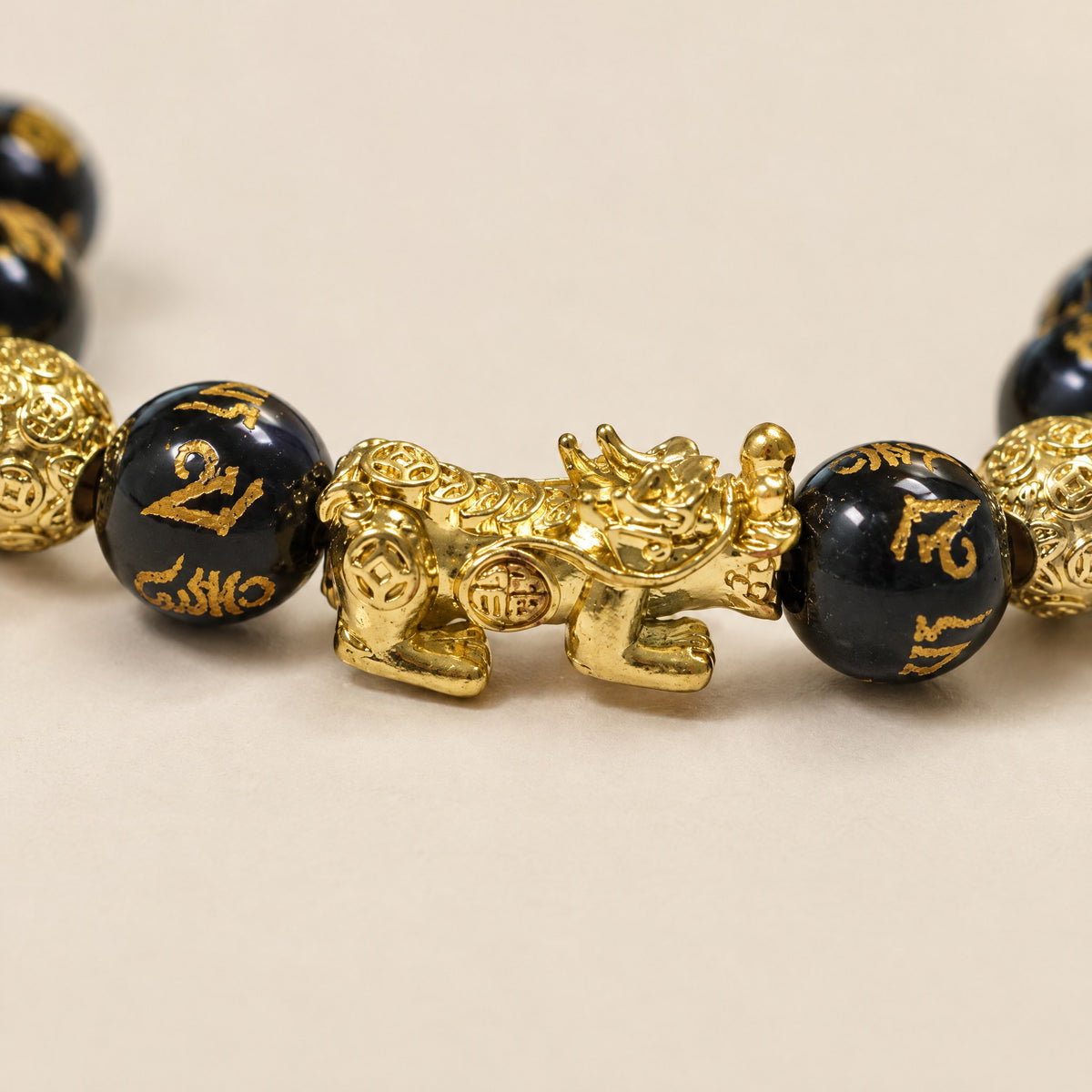 Close-up of the gold-tone Pixiu charm and engraved mantra beads