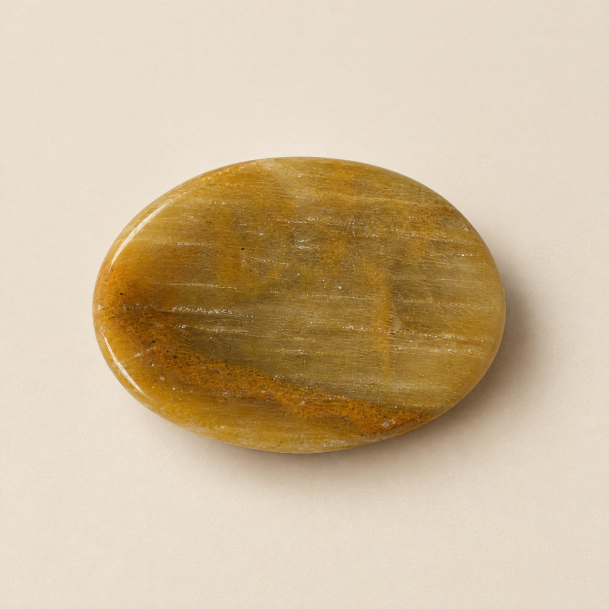 Polished yellow aragonite worry stone with thumb dip