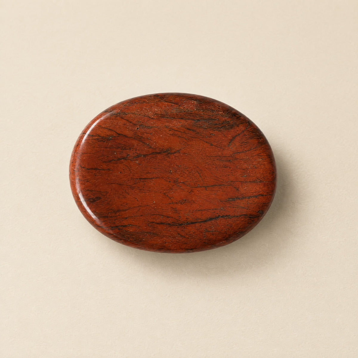Polished red jasper worry stone with thumb dip